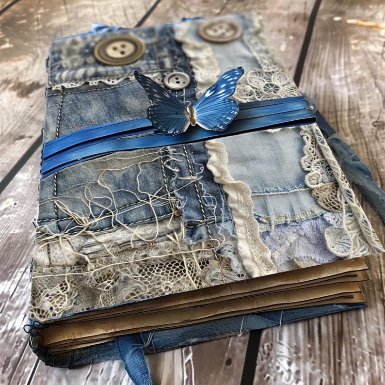 May include: A handmade journal with a denim and lace cover. The cover is decorated with blue and white fabric scraps, buttons, and a blue butterfly.