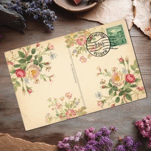 May include: Vintage postcard with floral illustrations of pink and yellow roses, green leaves, and small blue flowers. The postcard has a postmark and a green stamp. The background is a wooden surface with dried flowers.