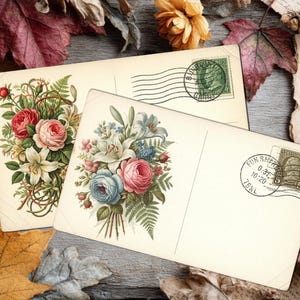 May include: Two vintage postcards with floral illustrations, featuring roses, lilies, and other flowers in shades of pink, red, and blue. The postcards have postage stamps and are surrounded by autumn leaves and dried flowers.