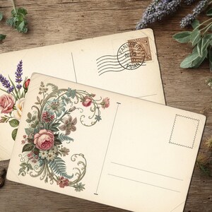 May include: Two vintage postcards with floral designs, one featuring roses and lavender, the other with an ornate arrangement. The postcards are on a rustic wooden surface, with a decorative key and sprigs of greenery.