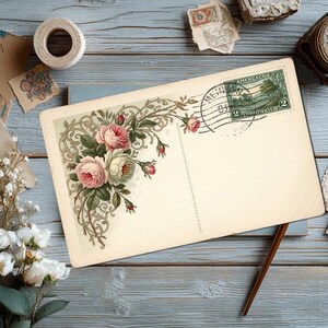 May include: Vintage postcard with a floral design featuring pink and white roses, a green stamp, and a postmark. The postcard is on a blue wooden surface, with other vintage items like stamps and flowers.