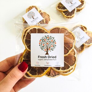 May include: A clear plastic bag filled with dried lemon slices. The bag has a label that says "Fresh Dried organic dehydrated fruit" and includes social media icons and website information.