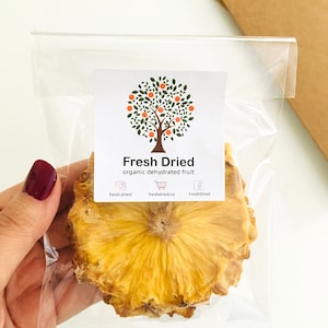 May include: A clear plastic bag with a single slice of dried pineapple. The bag has a label that says "Fresh Dried" and "organic dehydrated fruit".
