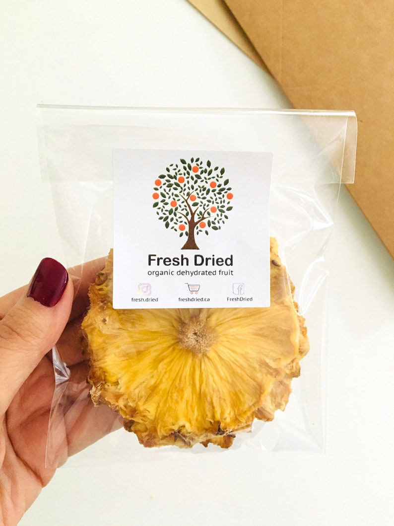 May include: A clear plastic bag with a single slice of dried pineapple. The bag has a label that says "Fresh Dried" and "organic dehydrated fruit".