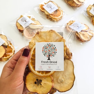 May include: A clear plastic bag filled with dried fruit slices. The fruit includes apple, pear, pineapple, and orange slices. The bag has a white label with the text "Fresh Dried organic dehydrated fruit" and social media icons.