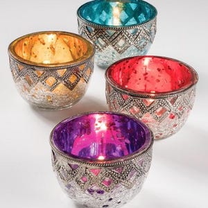 May include: Four decorative glass candle holders with silver metal trim. The holders have different coloured interiors: orange, teal, red, and purple. The glass has a textured, mercury glass appearance, and the metal trim has a geometric pattern.