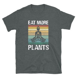 Pu&ograve; includere: Una t-shirt grigio scuro melange con una grafica vintage di una persona che medita con il testo "Eat More Plants" in bianco.