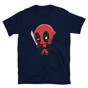 Puede incluir: Una camiseta azul marino con una imagen de dibujos animados de Deadpool sosteniendo una espada y haciendo un signo de paz.