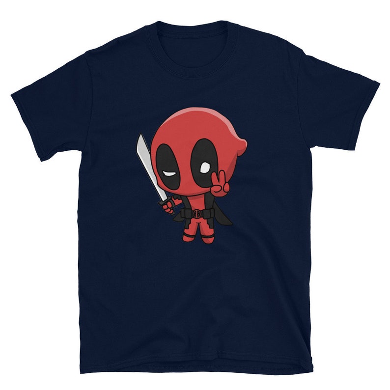 Puede incluir: Una camiseta azul marino con una imagen de dibujos animados de Deadpool sosteniendo una espada y haciendo un signo de paz.