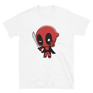 Puede incluir: Camiseta blanca con una imagen de dibujos animados de Deadpool sosteniendo una espada y haciendo un signo de paz. El personaje es rojo y negro con una m&aacute;scara blanca.