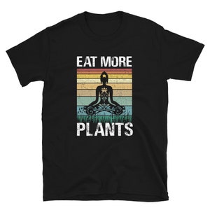 Pu&ograve; includere: Maglietta nera con una grafica in stile vintage di una persona che medita con il testo "Eat More Plants".