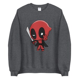 Könnte beinhalten: Ein dunkelgraues Sweatshirt mit einem Cartoon-Bild von Deadpool, der ein Katana hält und ein Peace-Zeichen macht. Der Charakter ist rot und schwarz mit einem weißen Auge.
