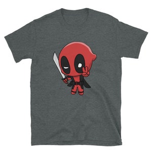 Puede incluir: Una camiseta gris oscuro jaspeada con una imagen de dibujos animados de Deadpool, un superh&eacute;roe, sosteniendo una espada y haciendo un signo de paz. La imagen est&aacute; en estilo chibi, lo que significa que es una caricatura con una cabeza grande y un cuerpo peque&ntilde;o.