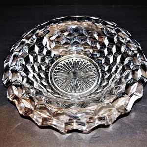 May include: A clear glass bowl with a diamond pattern. The bowl has a scalloped edge and a raised center.