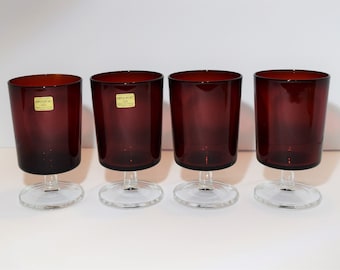 May include: Set of four dark red stemmed glasses with clear bases. Each glass has a label that reads "Enrolac".