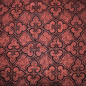 May include: A red fabric with a black paisley pattern. The pattern is intricate and detailed, with a repeating design of swirling shapes and leaves.