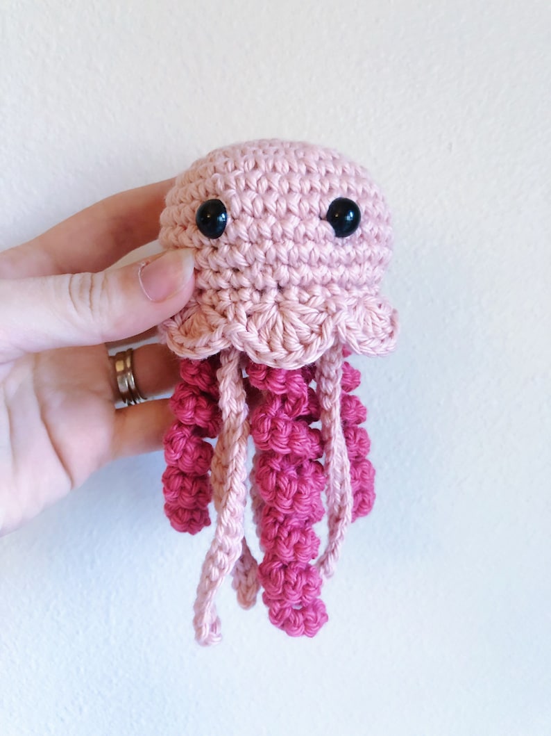 May include: A crocheted pink and red jellyfish toy with black eyes.