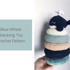 Peut inclure: Patron de crochet pour un jouet d'empilage de baleine bleue. Une baleine bleue en crochet avec un évent blanc est posée sur une pile de cinq anneaux en crochet colorés.