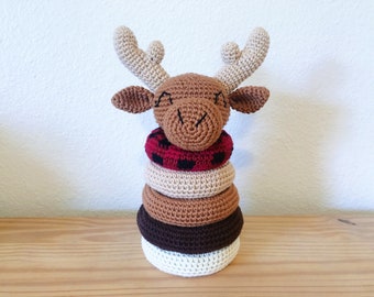 May include: A crocheted moose toy with a red and black patterned ring stacked on top of four other rings in brown, beige, and white.