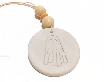 Peut inclure: Une décoration en céramique blanche avec un motif de fantôme, suspendue à une ficelle avec deux perles en bois.