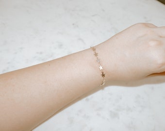 May include: A gold chain bracelet with small star charms.