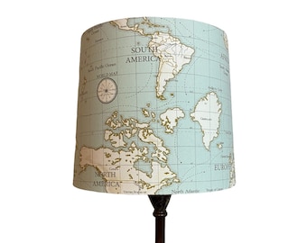 May include: A table lamp with a brown wooden base and a light blue lampshade featuring a vintage world map design.