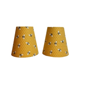 May include: Two yellow lampshades with a honeycomb pattern and black bees.