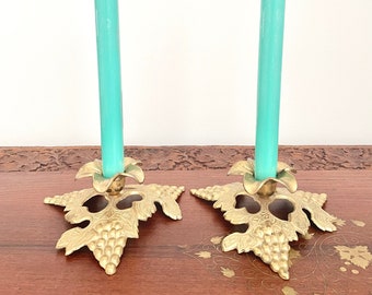 May include: A pair of gold metal candle holders with a grapevine design. Each holder has a teal candle.