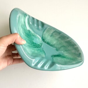 May include: A light blue ceramic ashtray with a swirl design. The ashtray has a deep well and a wide rim.