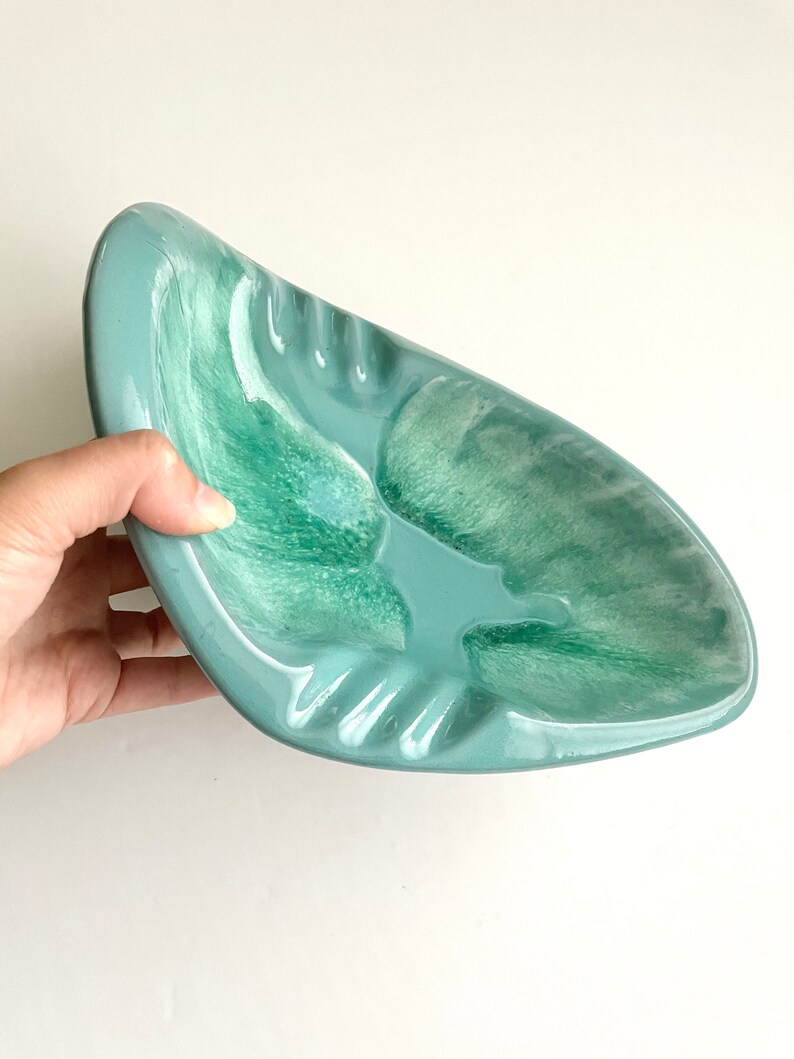 May include: A light blue ceramic ashtray with a swirl design. The ashtray has a deep well and a wide rim.