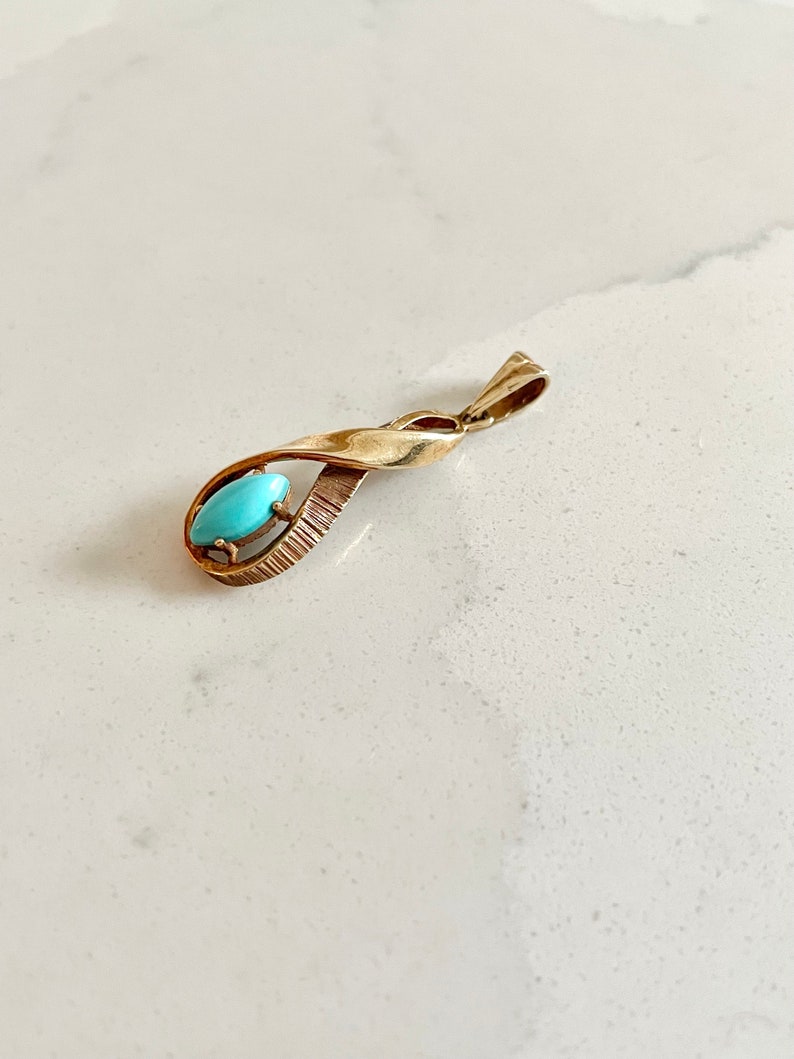 May include: A gold pendant with a turquoise stone set in a twisted design.