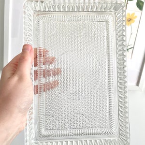 Puede incluir: Una bandeja rectangular de vidrio transparente con un patr&oacute;n de diamantes texturizado y bordes decorativos. La bandeja tiene dos asas y mide aproximadamente 30 cm de largo y 20 cm de ancho, perfecta para servir aperitivos o postres.