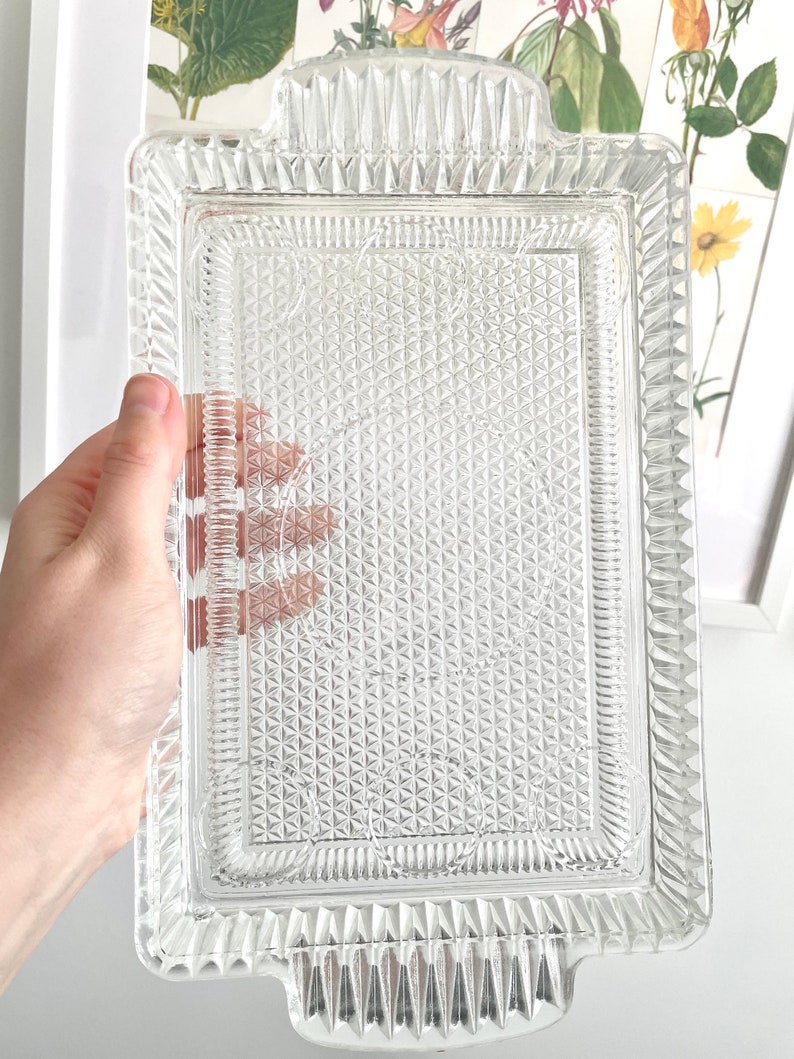 Puede incluir: Una bandeja rectangular de vidrio transparente con un patr&oacute;n de diamantes texturizado y bordes decorativos. La bandeja tiene dos asas y mide aproximadamente 30 cm de largo y 20 cm de ancho, perfecta para servir aperitivos o postres.