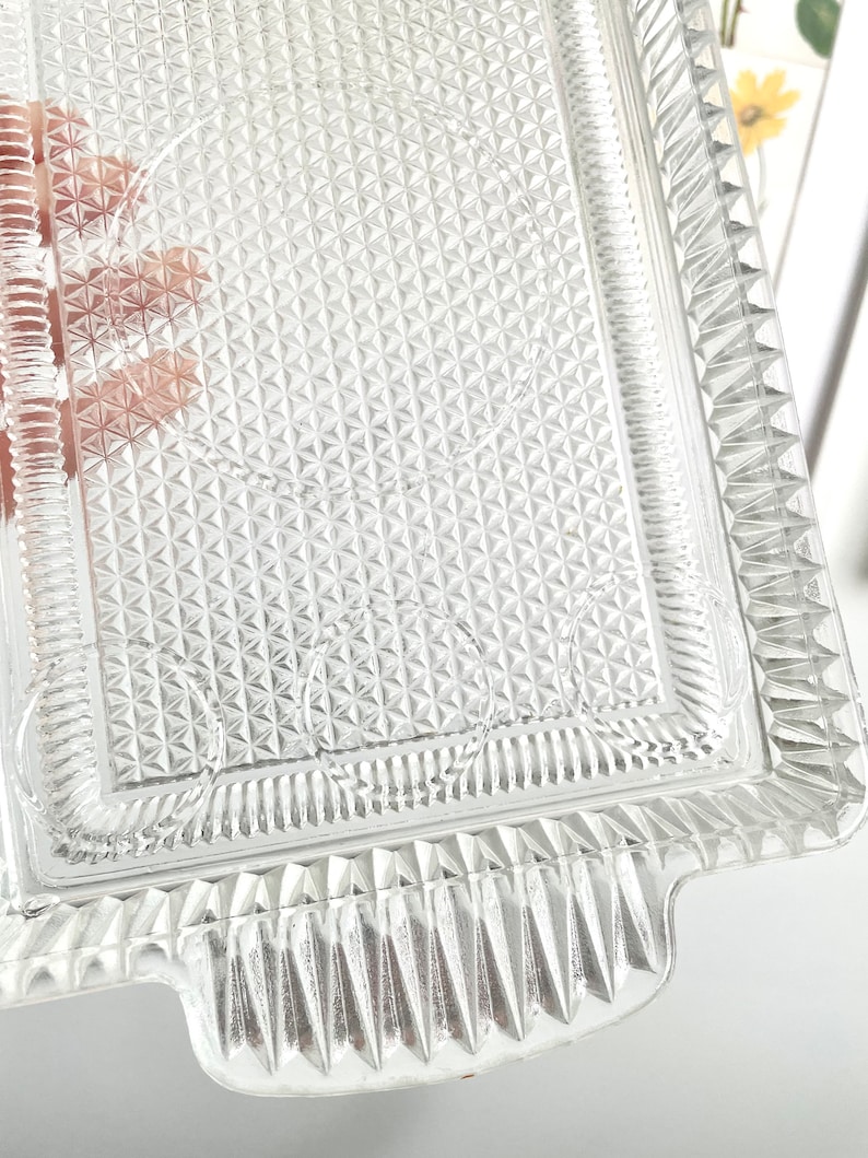 Puede incluir: Bandeja rectangular de vidrio transparente con un patr&oacute;n de diamantes texturizado y bordes decorativos. La bandeja tiene asas en cada extremo, ideal para servir aperitivos o postres.