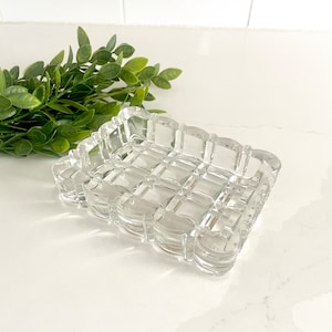 Puede incluir: Un plato rectangular de vidrio transparente con un patrón de rejilla y un borde festoneado.