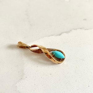 May include: A gold pendant with a turquoise stone set in a twisted design.
