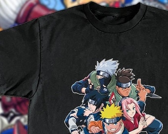 Puede incluir: Camiseta negra con un estampado gráfico de los personajes principales de la serie de anime Naruto. Los personajes son Naruto, Sasuke, Sakura, Kakashi y Shikamaru. El texto en la camiseta dice "Naruto" en japonés.