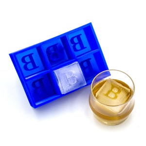 May include: Blue plastic ice cube tray with the letter "B" in each compartment. One ice cube with the letter "B" is in a glass of amber liquid.