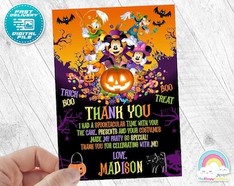 Puede incluir: Archivo digital con temática de Halloween con Mickey Mouse, Minnie Mouse, Donald Duck y Goofy. La tarjeta presenta una calabaza, murciélagos y las palabras "Thank You" y "Madison". La tarjeta es sostenida por una mano.