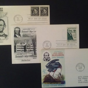 May include: Three white envelopes with stamps and postmarks. The first envelope features a black and white image of Abraham Lincoln with the text "Prominent Americans" and "First Day of Issue". The second envelope features a black and white image of a building with the text "Dartmouth College" and "First Day of Issue". The third envelope features a color image of a bird with the text "John James Audubon" and "First Day of Issue".