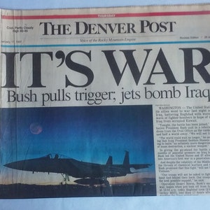 May include: A newspaper front page from The Denver Post with the headline "IT'S WAR" and the subheadline "Bush pulls trigger, jets bomb Iraq." An image of a fighter jet is visible.
