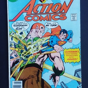 May include: A comic book cover featuring Superman battling a green and brown villain. The cover is blue and yellow with the title "Superman's Action Comics" and the text "Now--it's my turn!" and "Superman's shattering showdown with Amazo!"