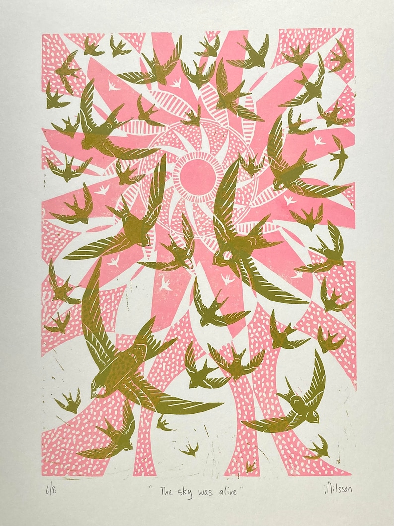 May include: A print featuring a flock of birds in flight, rendered in shades of olive green and pink. The birds are set against a stylized sunburst design. The text "The sky was alive" is at the bottom.