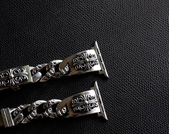 May include: Two silver watch bands with ornate, symmetrical designs. The bands feature a chain-link style and decorative clasps. The watch bands are displayed against a dark, textured background.
