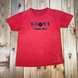 Op de afbeelding: Rood T-shirt met een zwarte spinnenafbeelding en de tekst "SPIDER-MAN". De korte mouwen tee heeft een ronde hals. Het shirt is gemaakt van een zacht materiaal en is geschikt voor vrijetijdskleding.