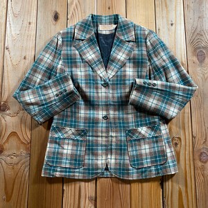 Op de afbeelding: Een blazer met lange mouwen en een ruitpatroon in tinten blauwgroen, bruin en wit. Het kledingstuk is voorzien van een reverskraag, twee opgestikte zakken aan de voorzijde, een sluiting met twee knopen en drie kleine knopen op elke mouwboord.