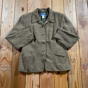 May include: A textured olive green blazer featuring a collared neckline, long sleeves, and a front button closure with four buttons. The jacket includes two front pockets and a Pendleton brand label on the interior collar lining.