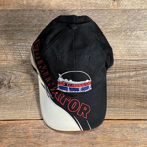May include: Black baseball cap with the words "Top Eliminator" in red and white. The cap has a white and black curved design on the side. The cap also has the words "National Hot Rod Association" on the front.
