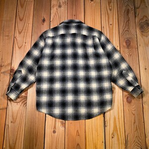 May include: A black and white checked button-down shirt. The shirt features long sleeves and a standard collar. The check pattern is composed of black and cream squares. The shirt is made from a soft, woven material.