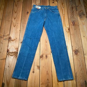 May include: Blue denim jeans with a classic five-pocket design. The jeans have a straight leg cut and a button and zipper closure. The denim has a medium wash with subtle fading and a red and white tag on the back pocket.